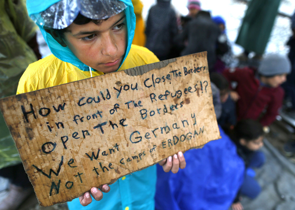 A migrant boy holds a sign declaring that he wants to travel to Germany, rather than remain housed in the refugee camps at the northern Greek border station of Idomeni, Greece.