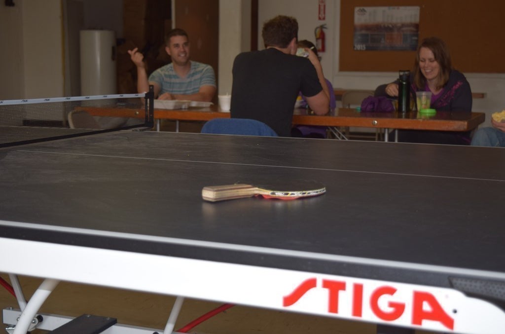 Code bootcamp attendees relax by a ping pong table in the basement of Church &amp; State.