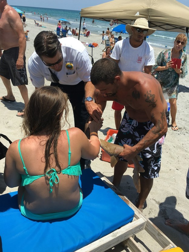 A beachgoer in Florida was bitten by a small shark on Sunday, then taken to a hospital with the 2-foot-long creature still attached to her arm.