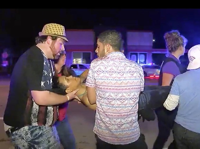 Christopher Hansen (left) helping others carry an injured woman outside Pulse.