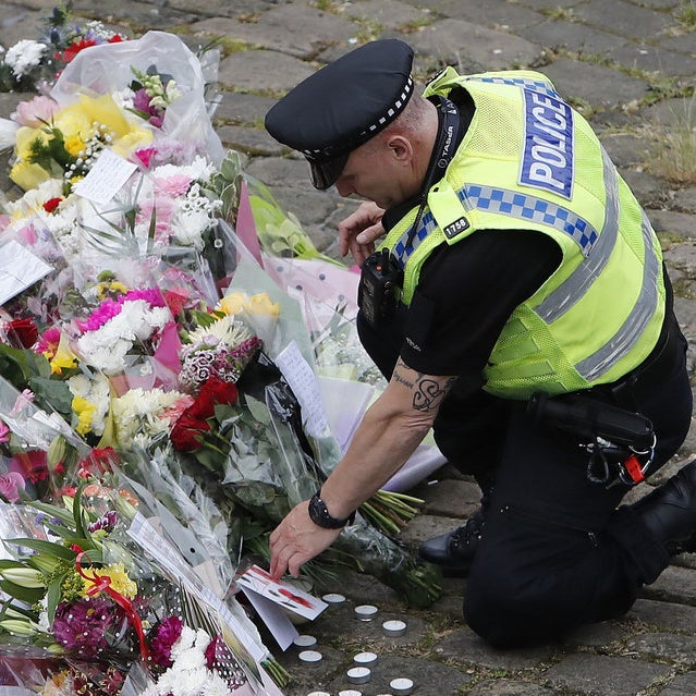 A police officers places flowers at a memorial in Birstall, West Yorkshire.