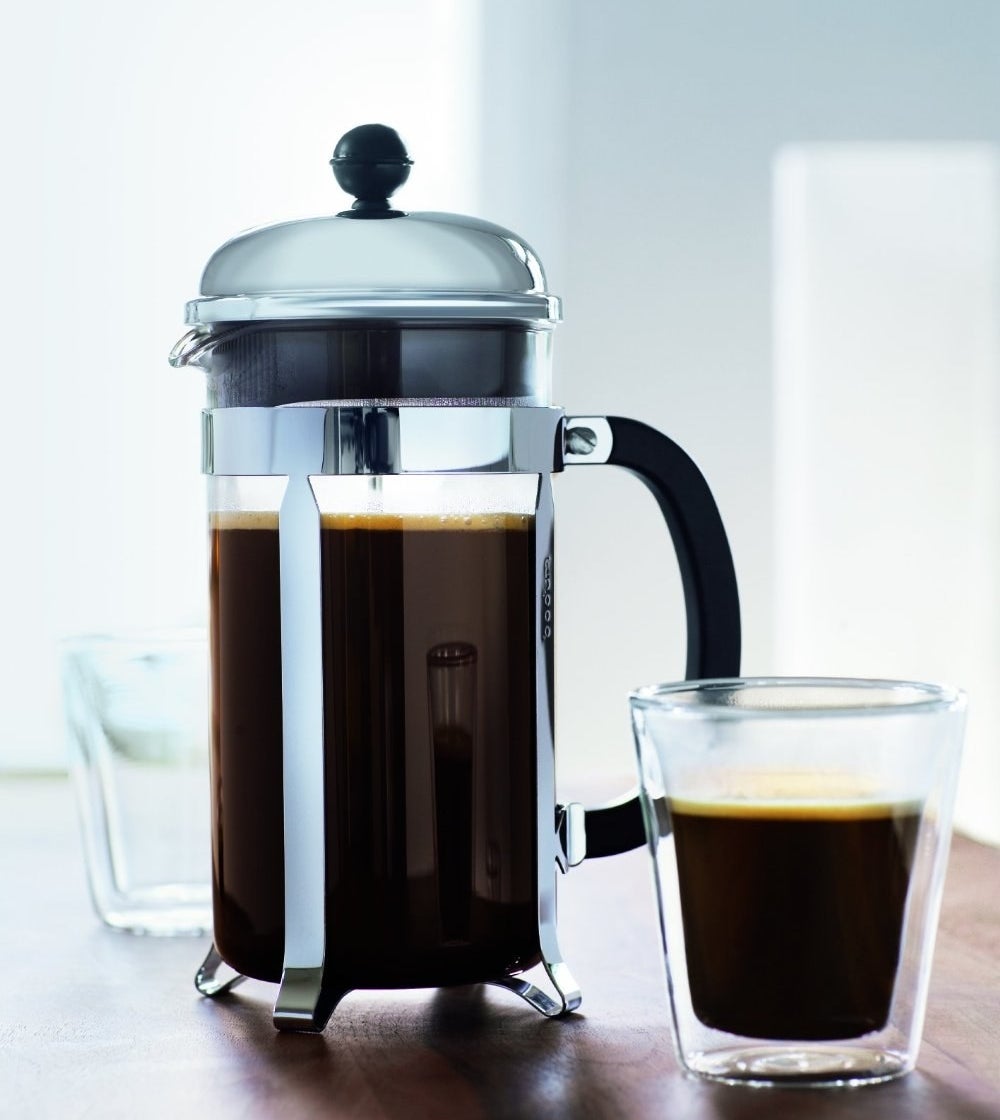 the French press next to a cup of coffee 