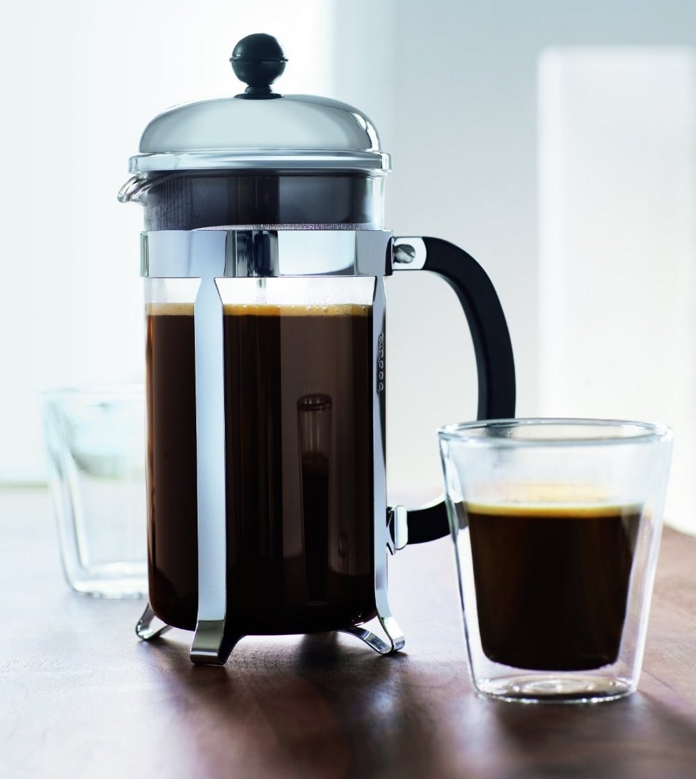 the French press next to a cup of coffee 