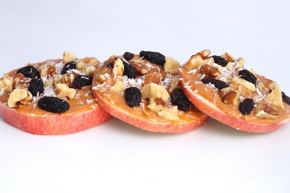 apple rounds with peanut butter, walnuts, raisins, and coconut