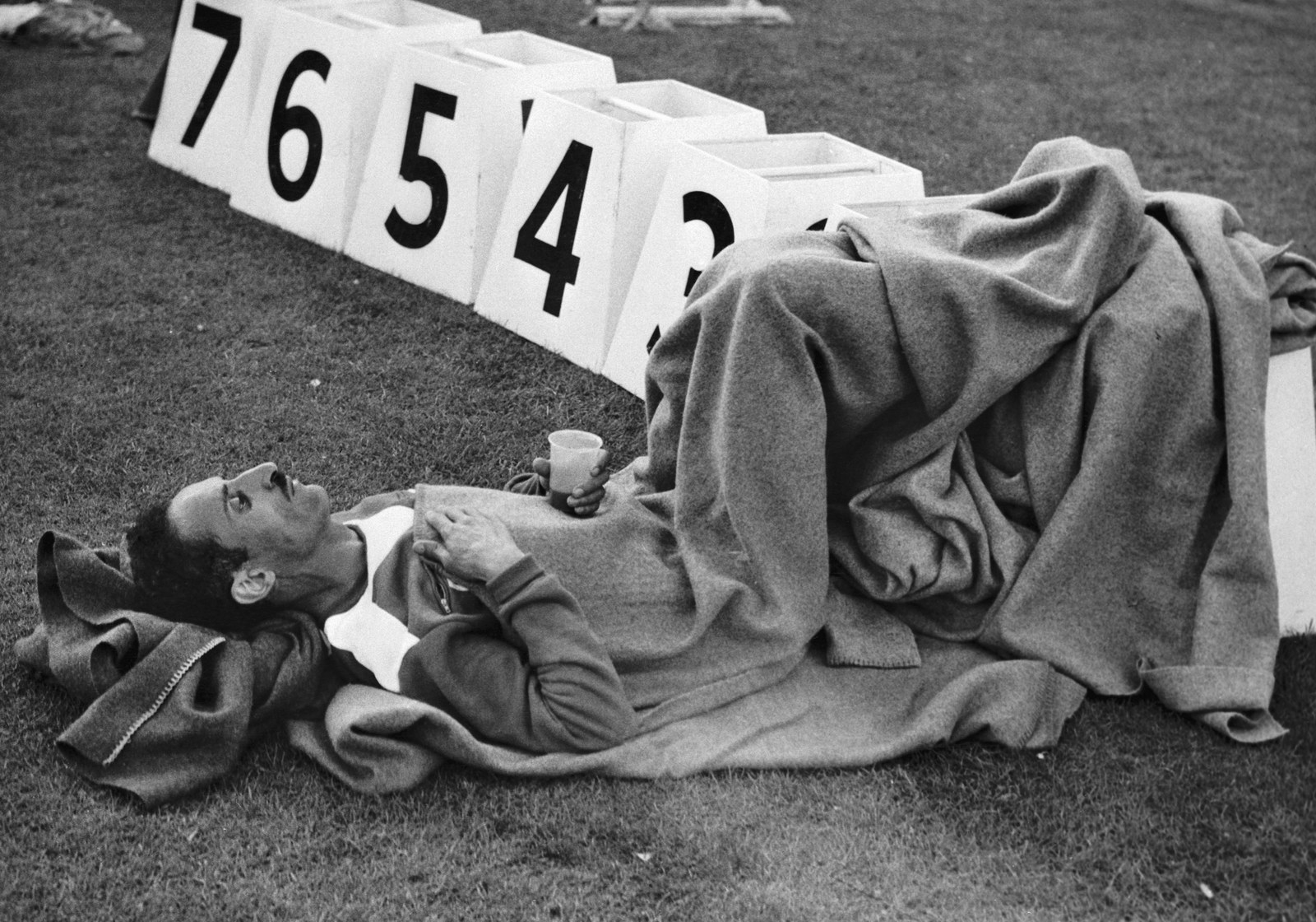 Alain Mimoun of France cooled down like a boss after coming in first at the Olympic marathon event - by lying on the ground wrapped in a blanket, with a drink in one hand. He made sure everyone knew his ranking though, by perching his feet on the first place marker.