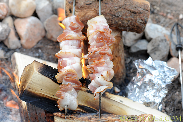 Cook bacon skewers over the campfire.