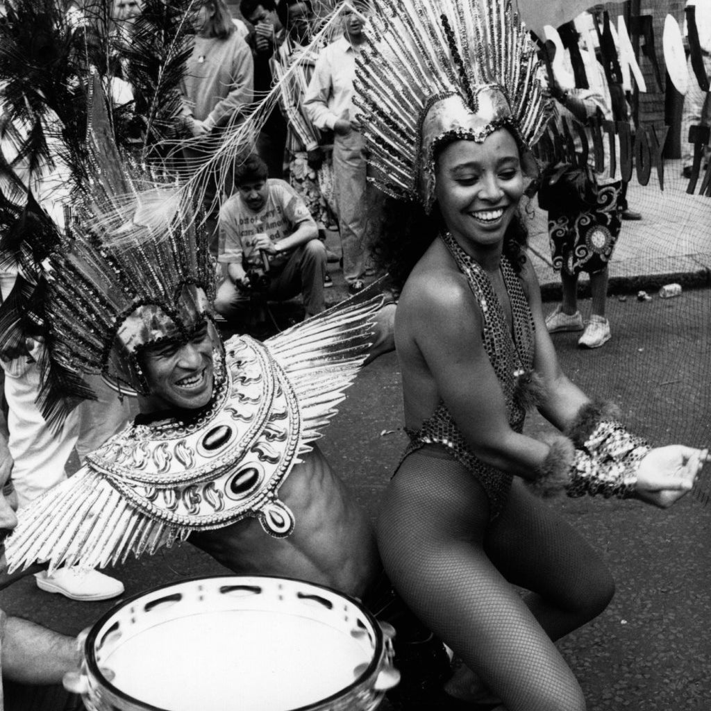 Performers in the Notting Hill Carnival procession wearing carnival costume and dancing for the crowds, August 1994.