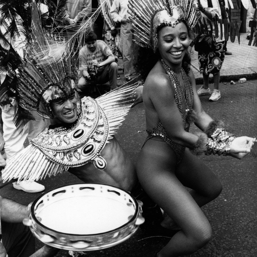 Performers in the Notting Hill Carnival procession wearing carnival costume and dancing for the crowds, August 1994.