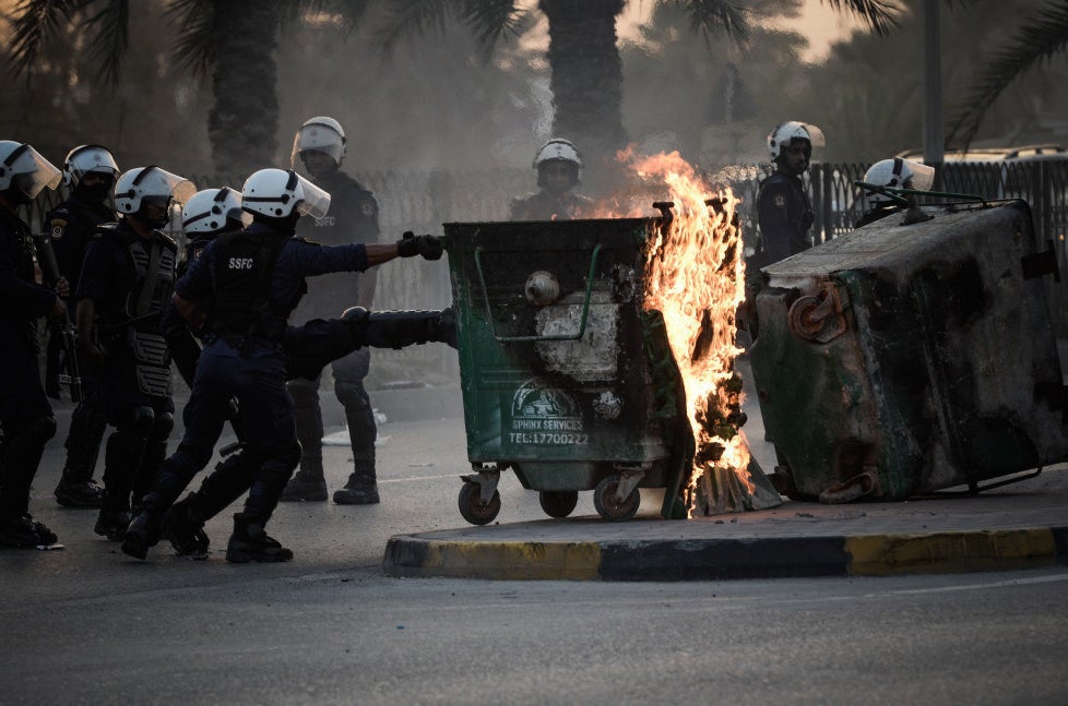 Bahraini riot police push burning bins that were set on fire by protesters in the village of Karranah, west of Manama, on 1 March 2013.