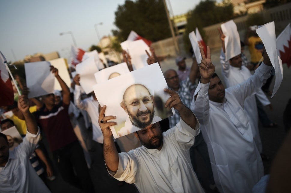 Bahraini protesters hold placards bearing the portrait of jailed former MP Sheikh Hassan Isa during a demonstration on 28 August 2015.