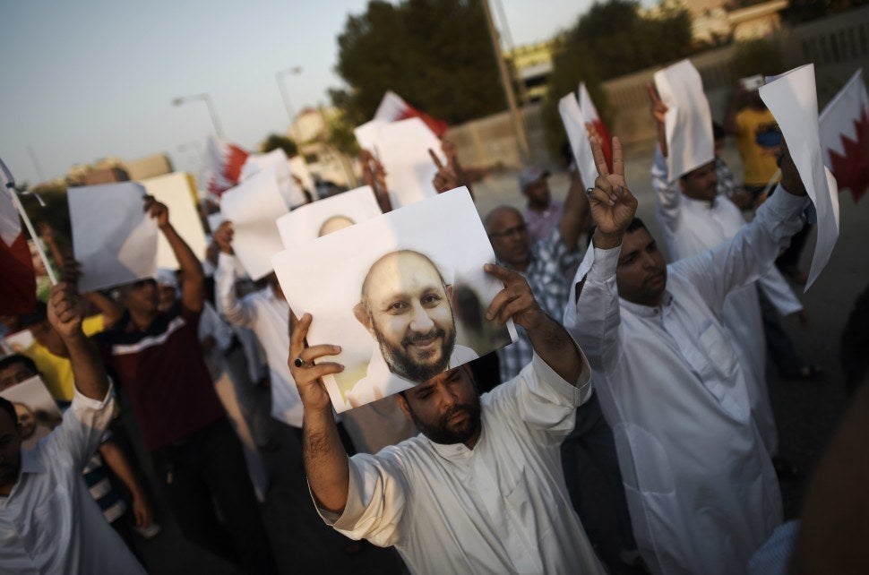 Bahraini protesters hold placards bearing the portrait of jailed former MP Sheikh Hassan Isa during a demonstration on 28 August 2015.