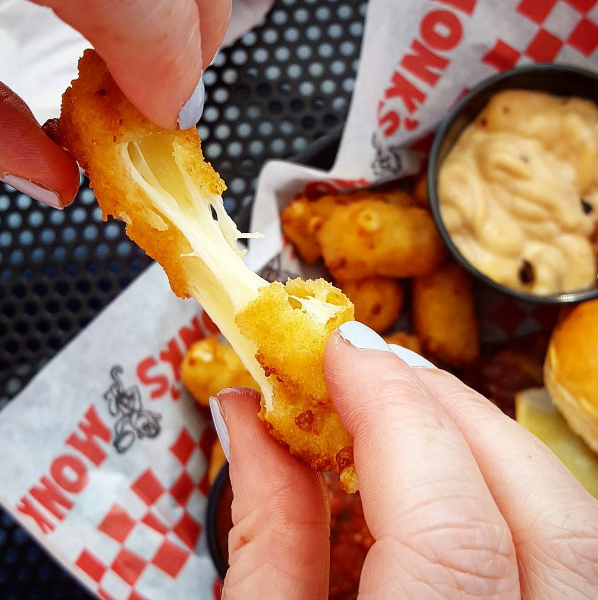 A long, slow pull of cheese from a fried cheese curd.