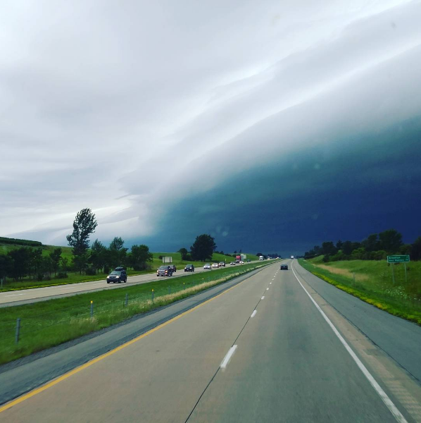 A nearly empty road with what could be tornado weather up ahead.