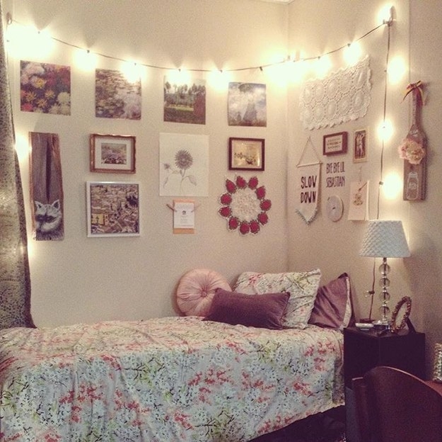 Room with twin bed, warm fairy lights, wall posters and hangings, and a mauve-pink color scheme
