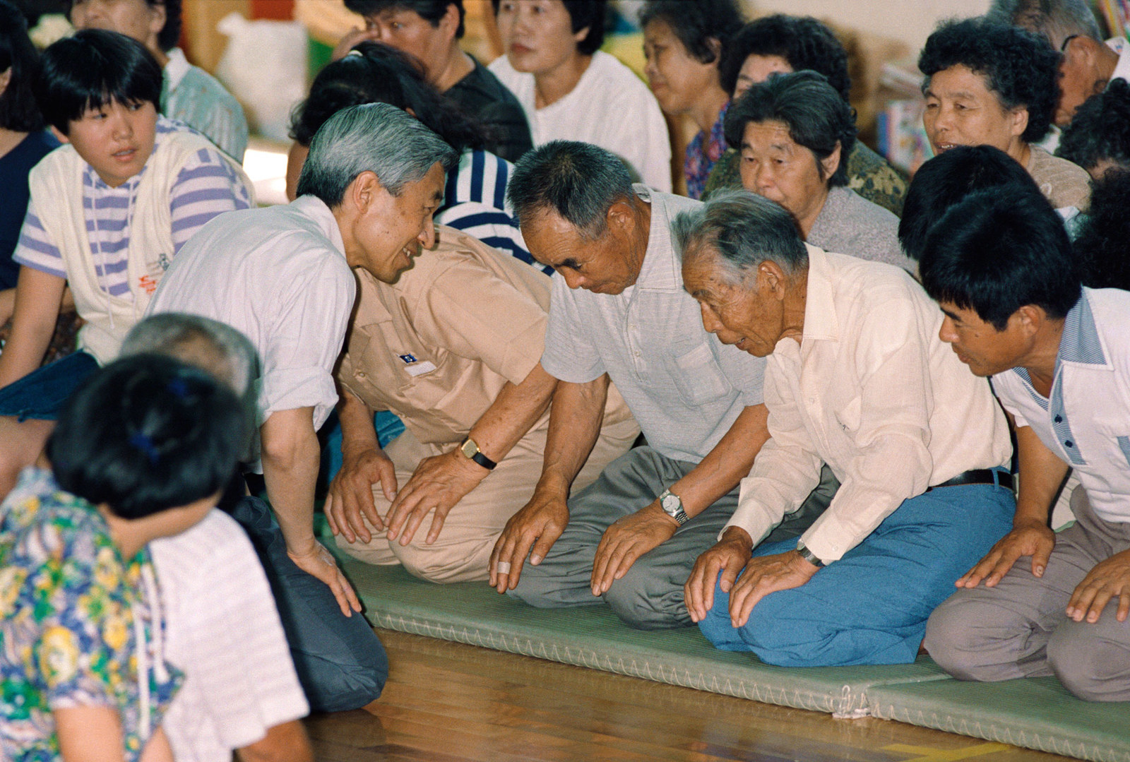 1991年、中学校の体育館に避難している住民と膝を交えて被災の様子をお聞きになる天皇陛下=長崎県高来郡布津町の布津中学校