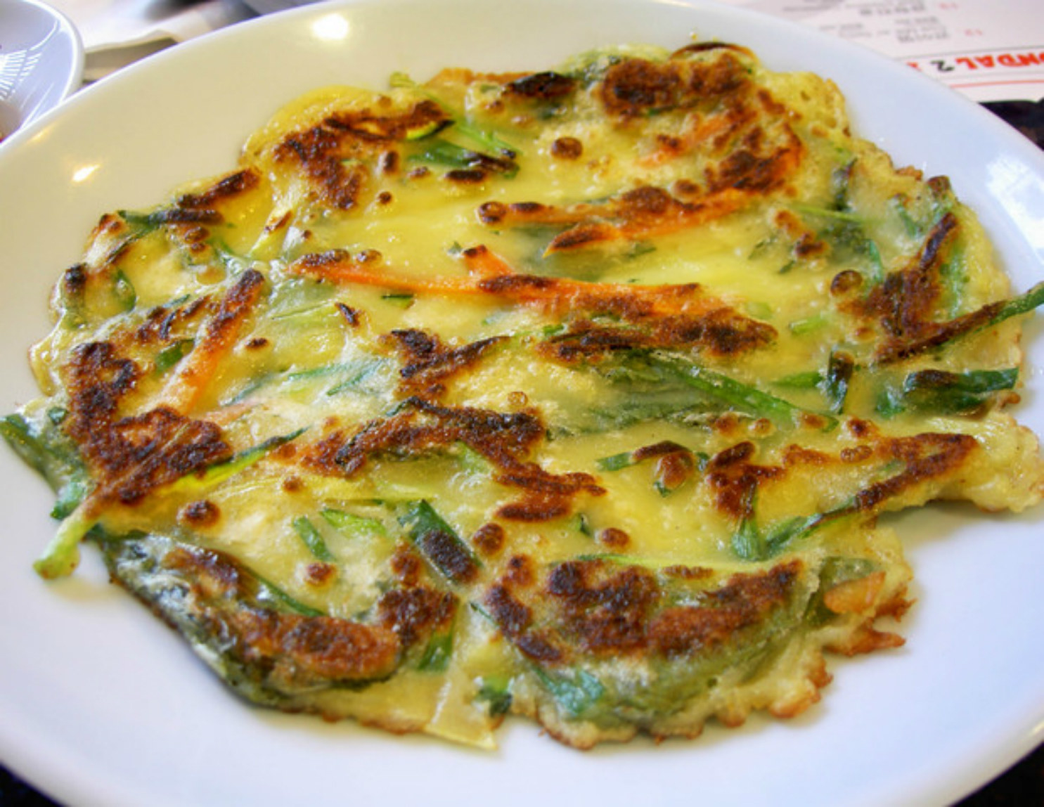 Kimchijeon or Kimchi pancakes are flour pancakes with chopped spicy pickled cabbage (kimchi) and scallions.The other Korean variant, hotteok, is made of sweet wheat-based dough which includes yeast and looks more like bread. The fillings are also sweet: honey, syrup or caramel. The cakes are pressed to melt the filling and roast the outside a little bit. The jeon pancakes are more like the Japanese recipe. Fried chicken, seafood, or vegetables are covered with the pancake mix.