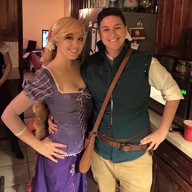 One person wearing a purple dress and one person wearing a blue vest with a belt and satchel