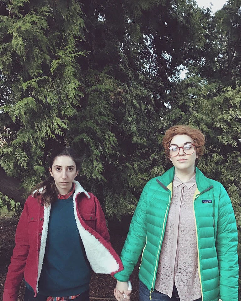 One person in a red jacket and one person in a green jacket