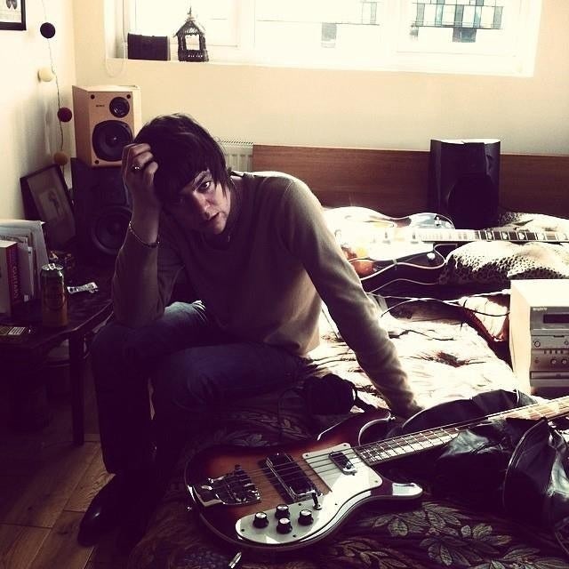 A photo of Patrick with his guitar in his bedroom.