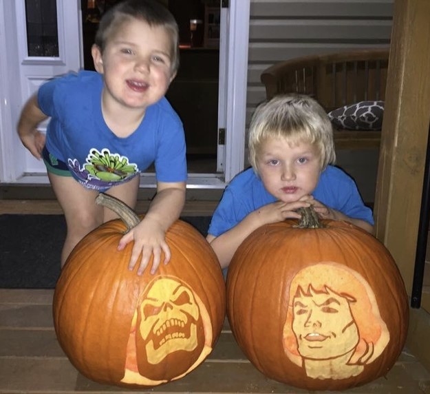Skeletor and Hee-Man pumpkin carvings with little boys standing by them