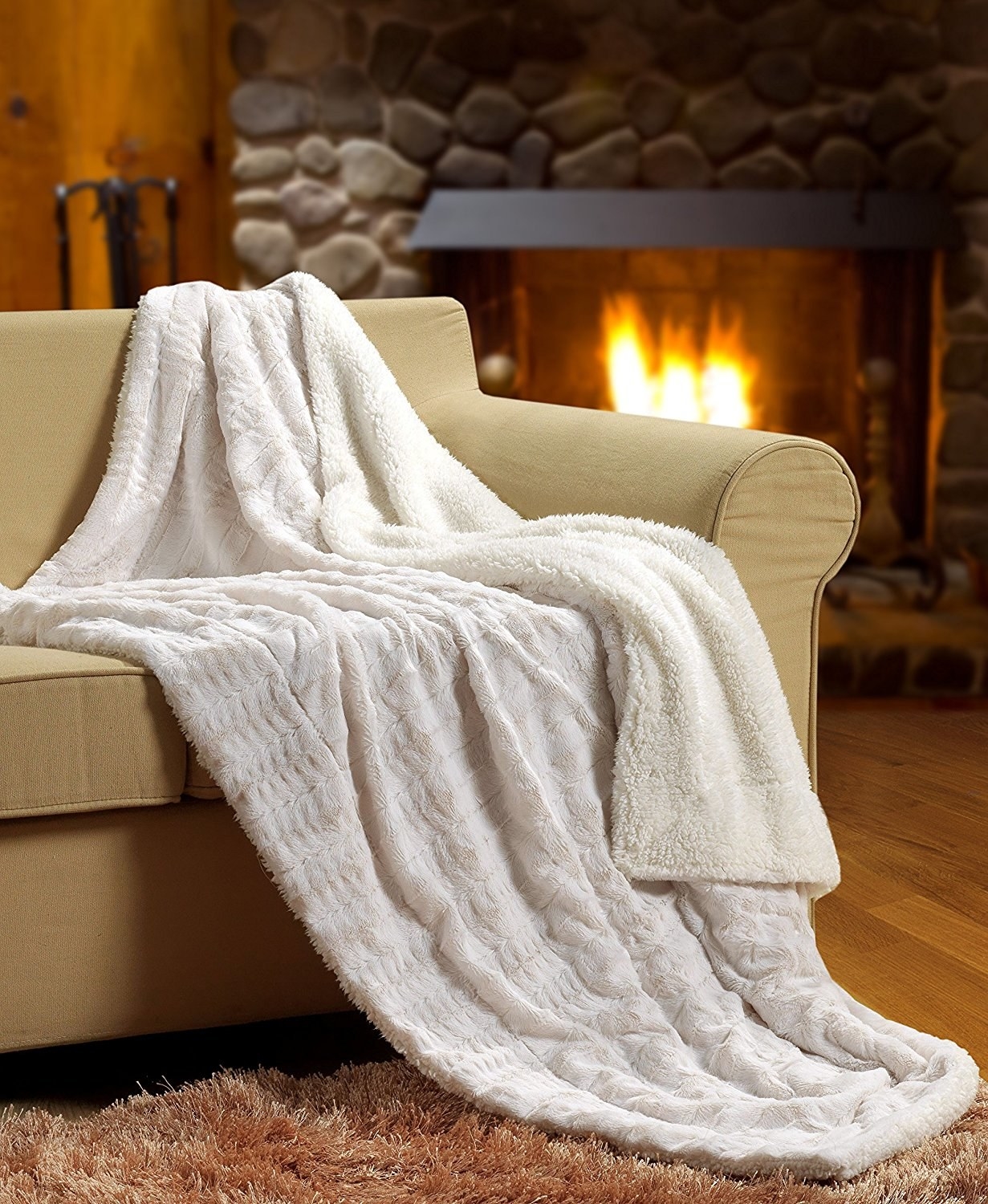 white faux fur fuzzy looking throw on a couch in front of a fire