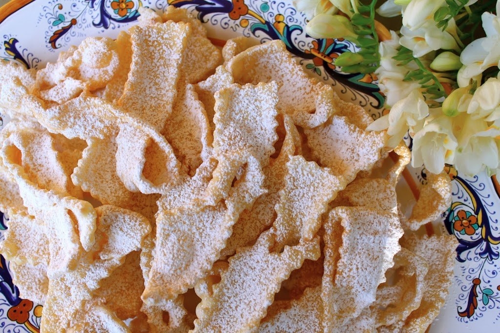 Flaky slices of sugar-dusted fried dough curls on a plate