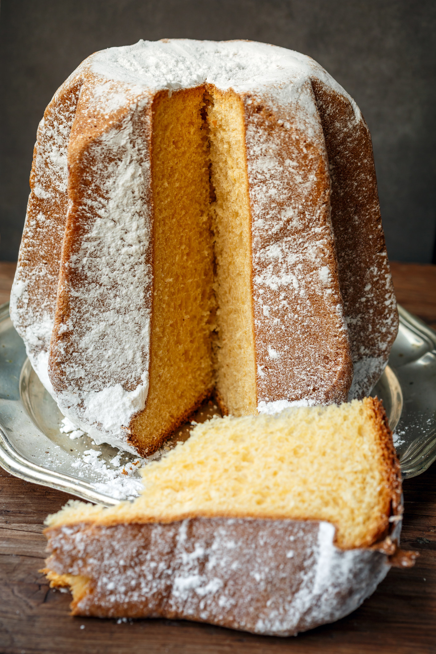A tall pandoro with a fat slice resting next to it