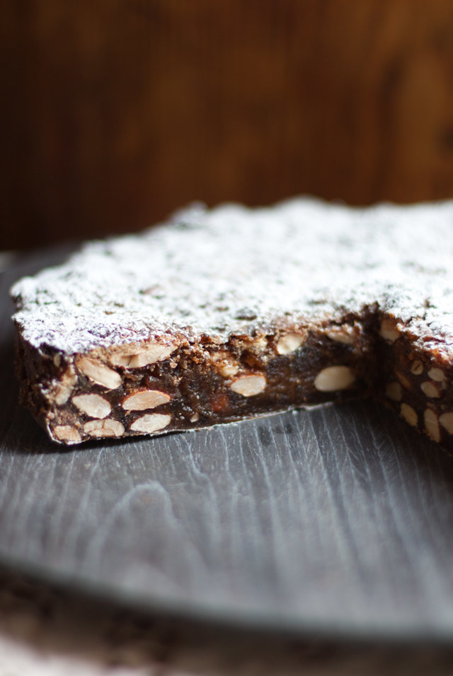 Dense-looking panforte sliced to show that the inside is filled with nuts and fruit bits