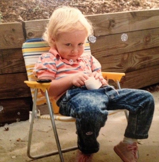 A young child wearing jeans and a T-shirt and slouched in a beach chair