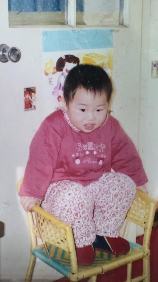 A toddler crouched in a small chair and wearing a &quot;Sweet&quot; top and pants