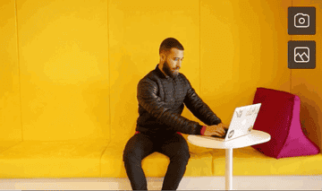 A person sits on a bench on their laptop, then raises their leg into a seated pigeon stretch