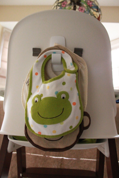 Stick a command hook on the back of a high chair to hang bibs.