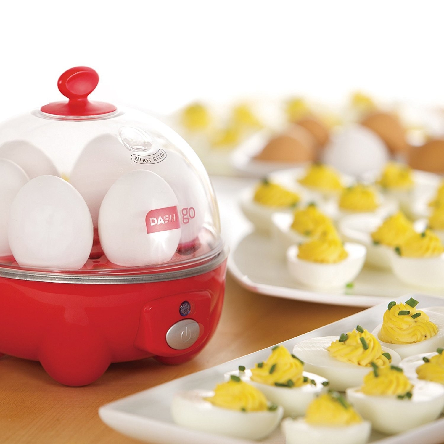 egg cooker with deviled eggs on a plate beside of it