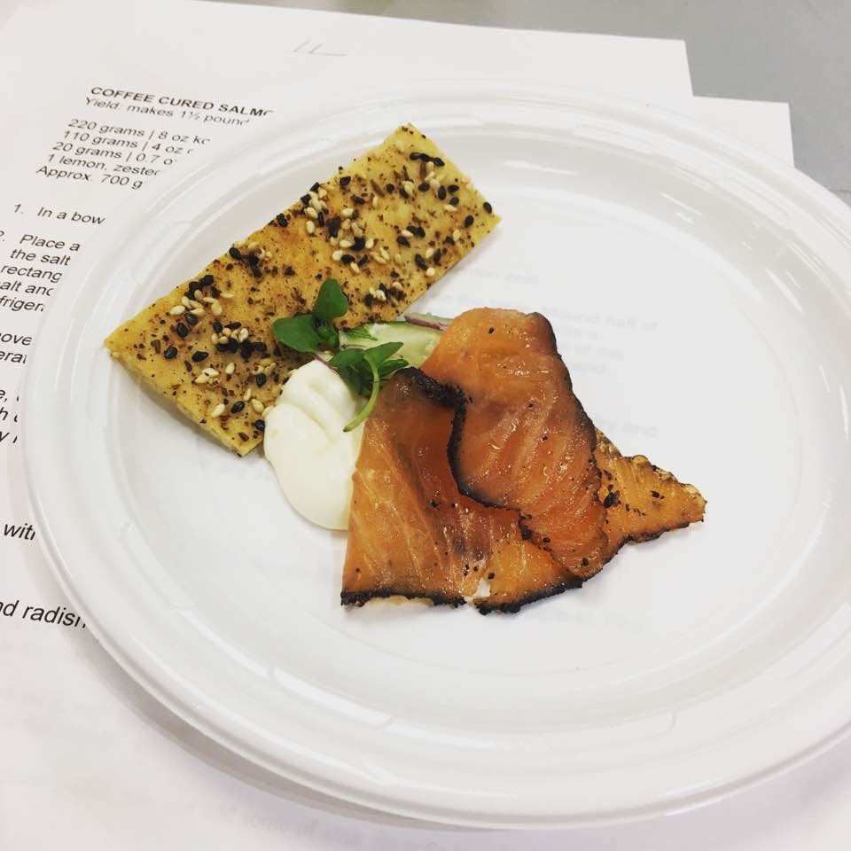 Presented by James Briscione, the ICE Director of Culinary Development, the Coffee Cured Salmon is seasoned with kosher salt, granulated sugar, ground coffee, and lemon zest. The dish is served with flatbread brushed with oil and dusted with Soom Soom Spice, cream cheese, shaved cucumbers and radish, and fresh dill.