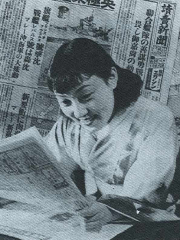 明日さんの1日に迫ったグラビア特集「素顔」。1941年(昭和16年)12月10日、マレー沖海戦の新聞記事を笑顔で眺めている。