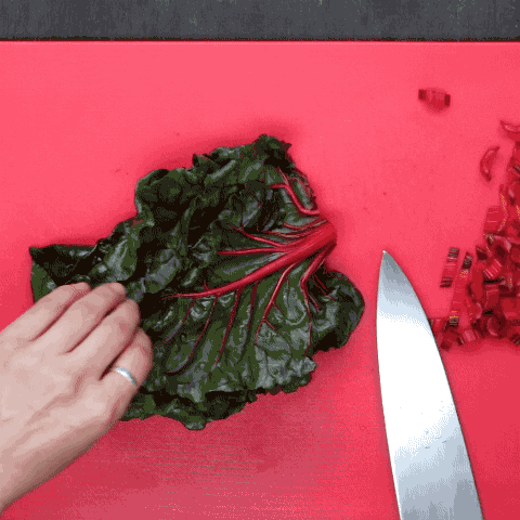 1. Place the chard leaves on top of each other. 2. With a chef’s knife, slice the chard stems until reaching the leaves.3. Roll the leaves up.4. Finely slice the leaves perpendicular to the roll.