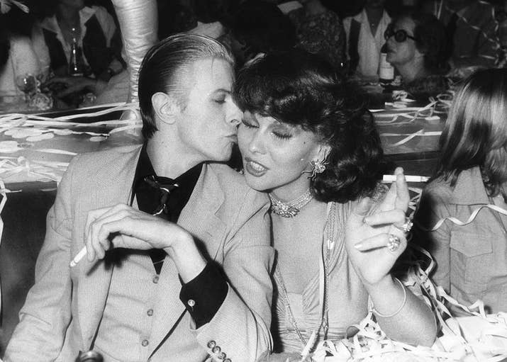 David Bowie and Dutch actor and singer Romy Haag have a smoke at the Alcazar nightclub in Paris during 1976.