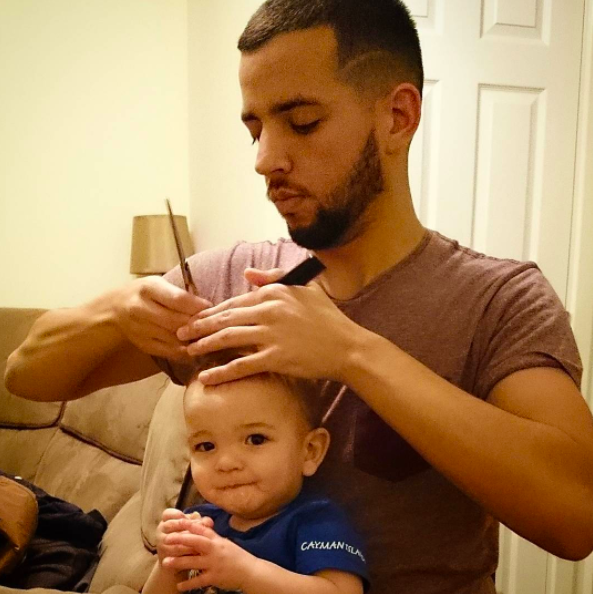 The first haircut on the head of a little boy in his life. A man is a father  who cuts his son's hair. Shave the curls off the baby's head with an