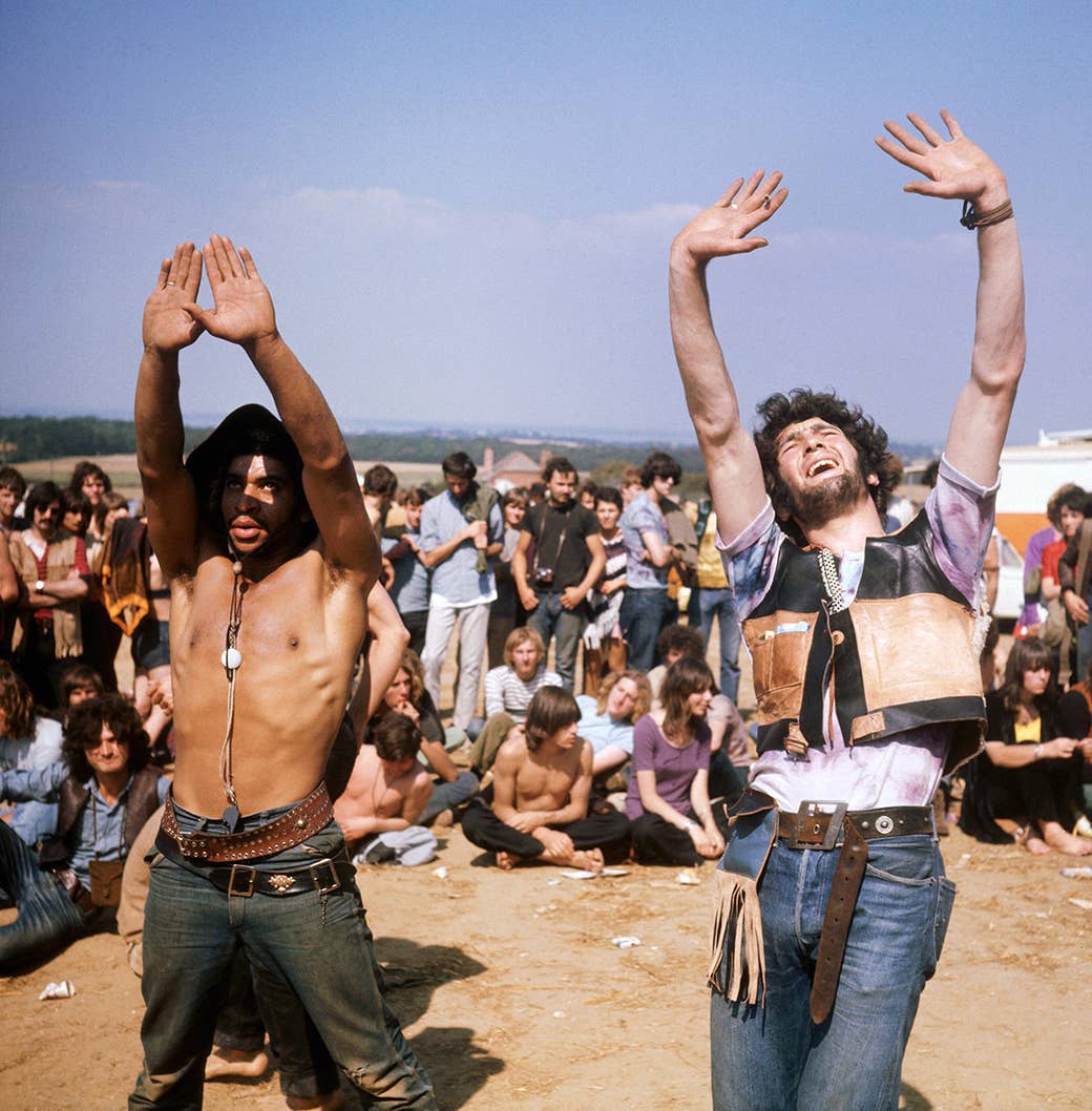 Um grupo de hippies assistir como vários outros dançar durante a Ilha de Wight Festival em 1969.