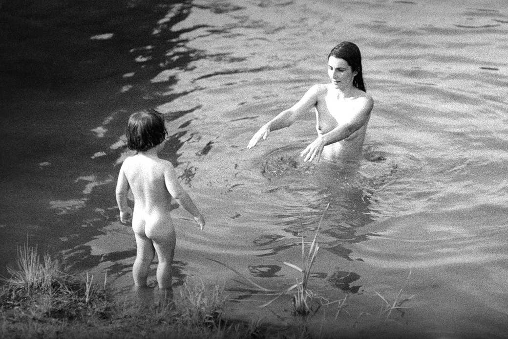 Uma mãe e sua criança nadam no lago durante a conferência alternativa dos meios na faculdade de Goddard em 1970 em Vermont.