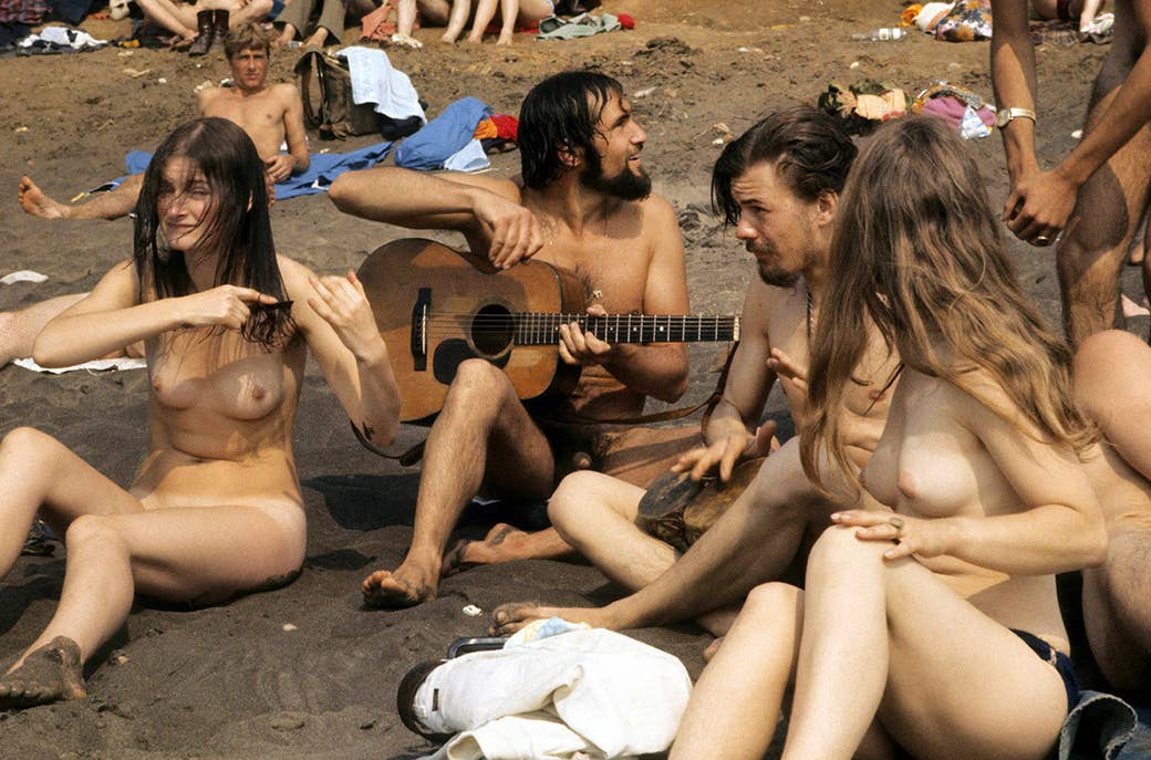 Um grupo de salão nu dos hippies na praia durante a ilha do festival do Wight em 1969.