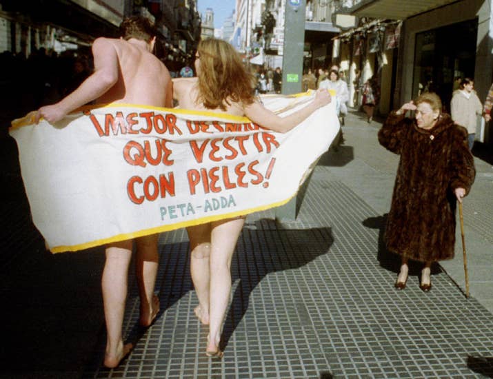 Una mujer con un abrigo de piel observa a dos activistas de PETA que se manifiestaron en Madrid el 20 de enero de 1994.