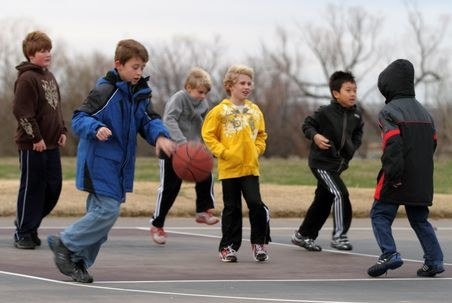 In middle childhood boys spend their play time a little differently than girls. Boys like to be outdoors and they typically hangout with a larger group. Instead of playing inside and talking about different things, they like to play competitive games against each other. This picture displays a typical setting for boys when they hangout during middle childhood. They are playing a competitive game(basketball), outdoors, and with a large group.