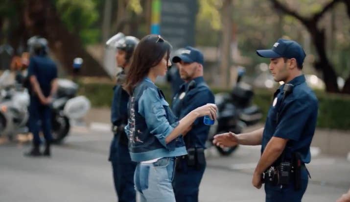 Los poderes mágicos de la Pepsi hacen que el policía se una a la causa y todos gritan en celebración.