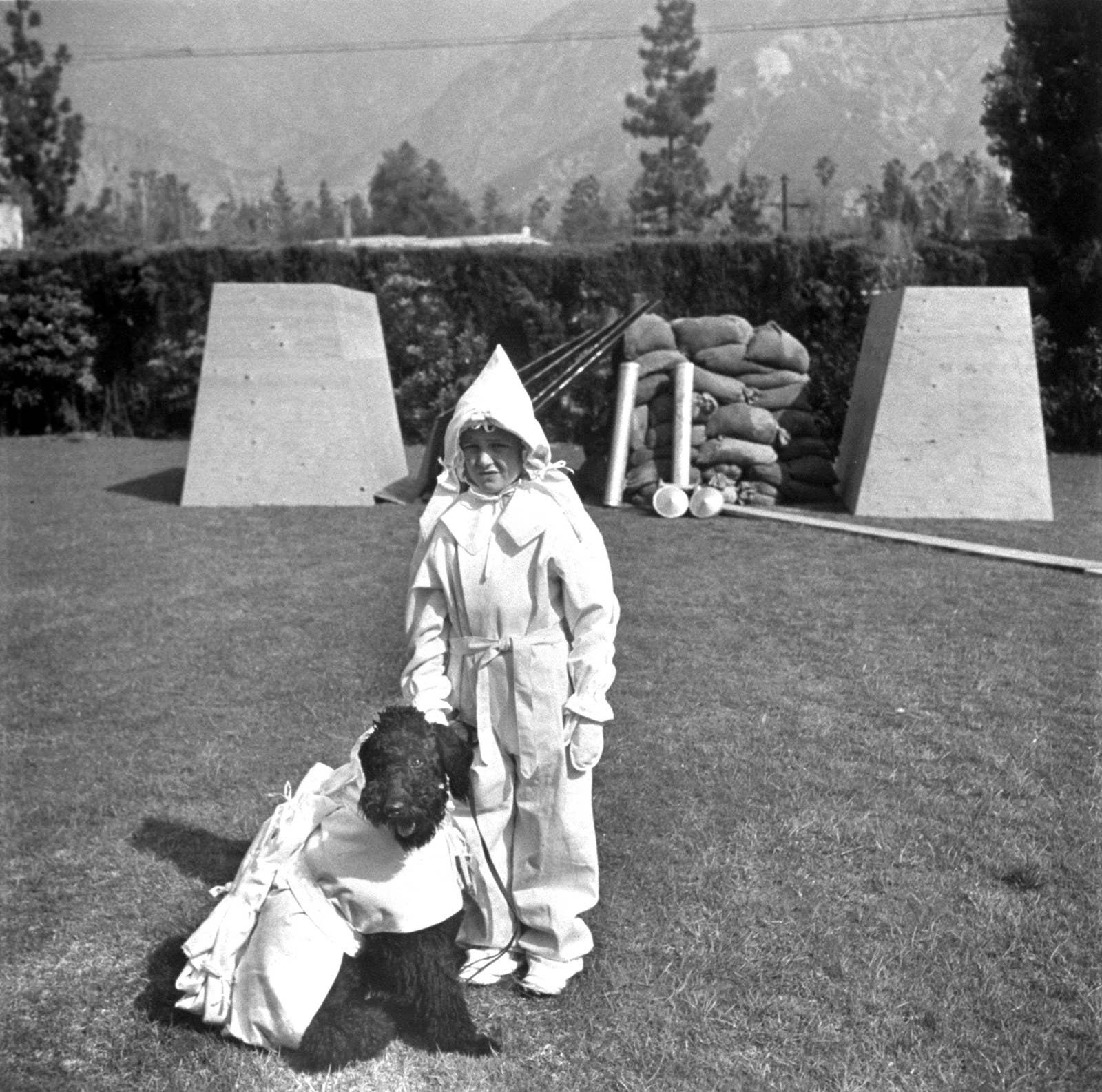 A boy and his dog model the latest fashions in atomic protection in front of their bomb shelter in 1951.