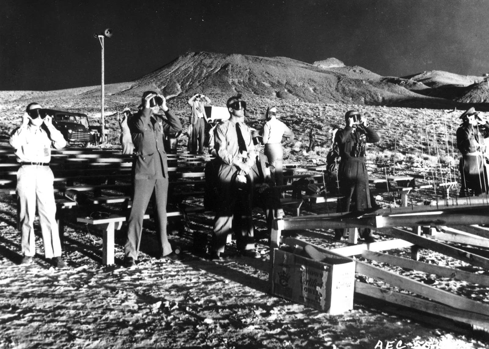 Observers wearing protective eyewear witness the detonation of nuclear artillery shell, codenamed 'Grable,' at the Nevada Proving Grounds on May 25, 1953. The long shadows are the result of the nuclear fireball. The shot was the 10th in a series of 11 nuclear detonations conducted in Operation Upshot–Knothole and marked the first time a nuclear device had been fired from a cannon.