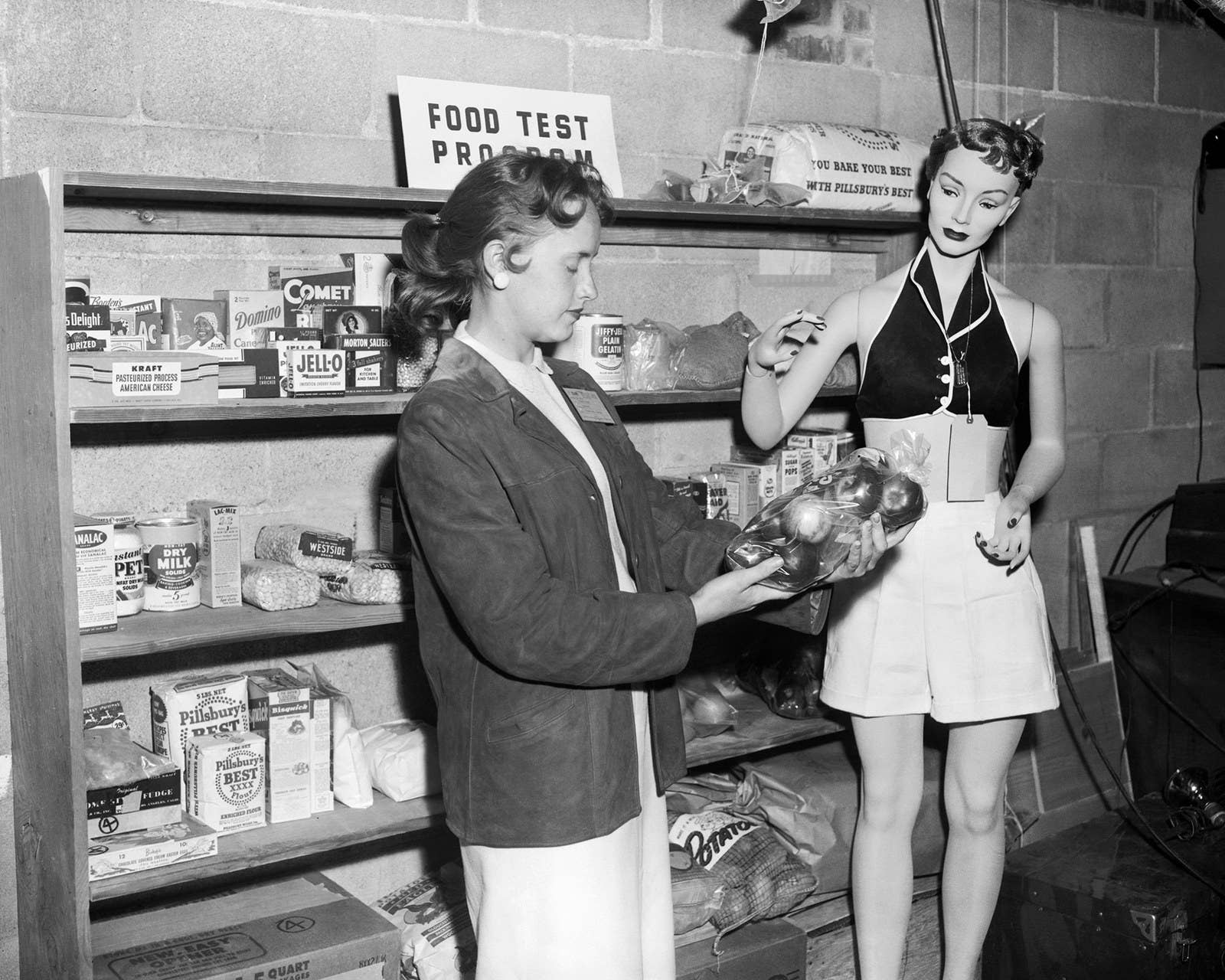 A woman sets up a grocery store scene at a Nevada test site dubbed 'Doom Town,' where the effects of an atomic blast would be tested on a variety of subjects in April 1955.