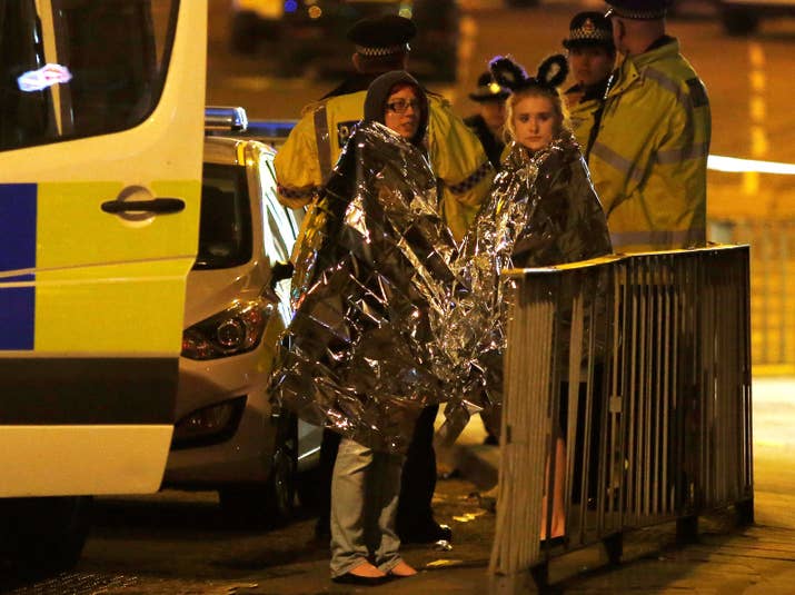 Two women wrapped in blankets stand near the Manchester Arena Monday night.