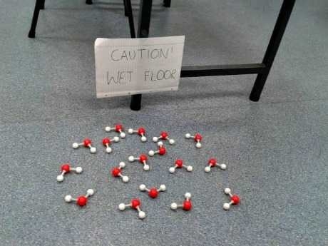 a caution wet floor sign with H20 models on the ground