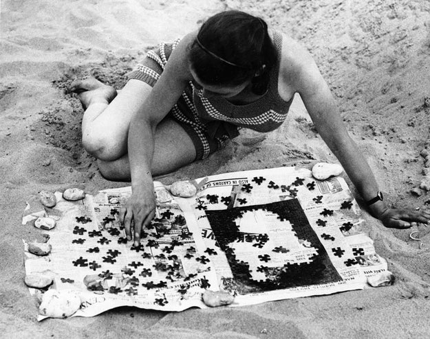This lady working on a puzzle, because sand is a perfect flat surface and the pieces definitely won't get lost.